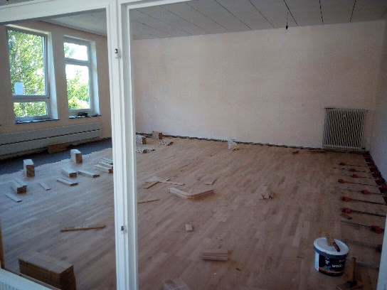 Parkettverlegung eines Vollholzparkettbodens in einem Eurythmieraum durch Boden-Frost Parkett in Osterholz-Scharmbeck, mit sichtbaren Parkettstäben und Verlegearbeiten.